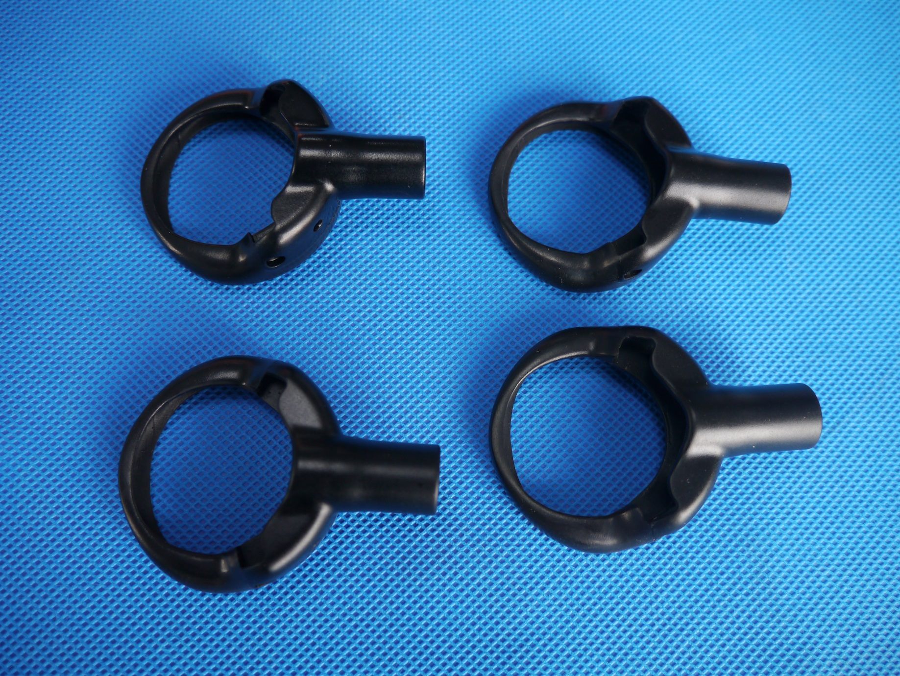 Four black overmolded circular parts on a blue work surface